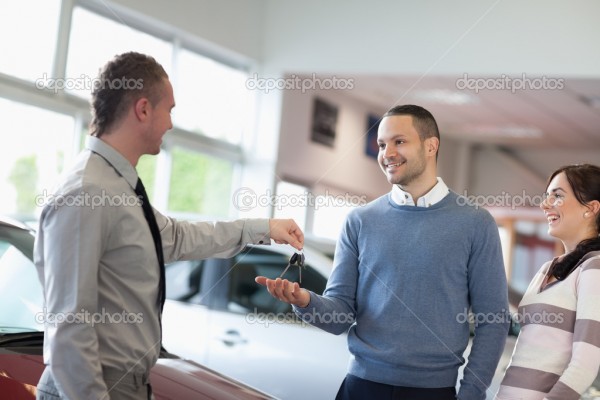 Salesman giving car keys to a smiling couple
